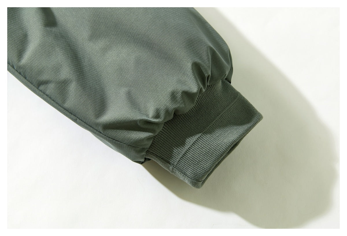 Close-up of a sage-green jacket sleeve ending in a dark ribbed cuff.
