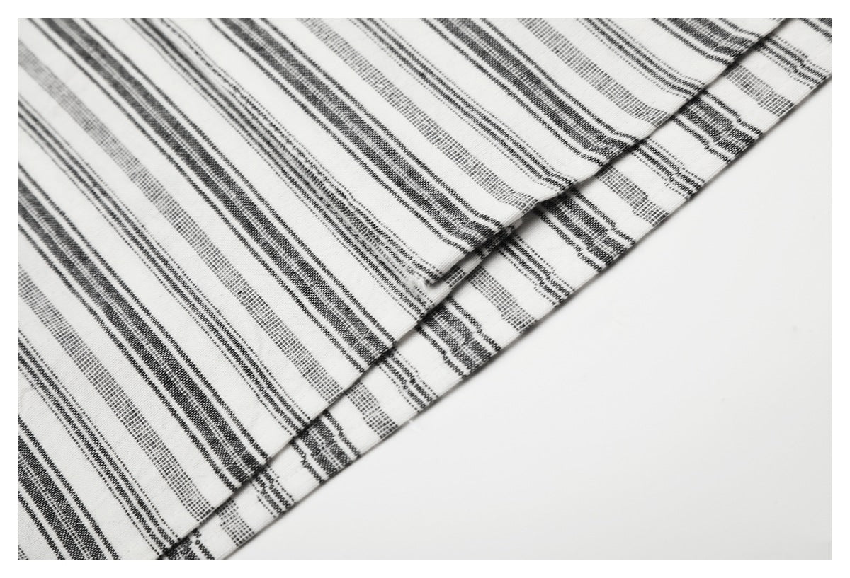 Close-up of the striped shirt's stitched hem and fabric edge.