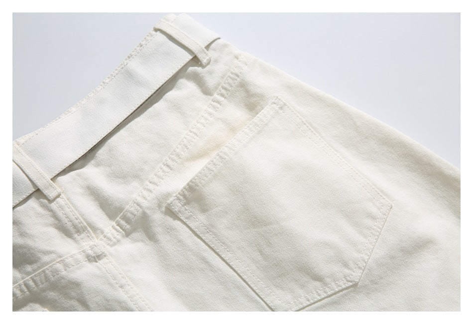 Close-up of off-white trousers showing a stitched rear pocket, belt loop and seams.