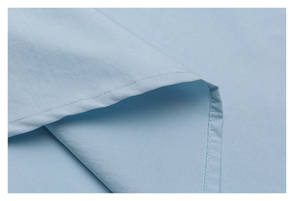 Close-up of a folded edge and stitched hem on a light blue garment.