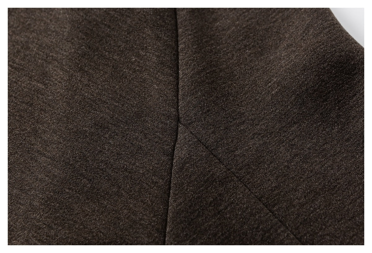 Close-up of dark brown coat fabric and intersecting stitched panel seams.