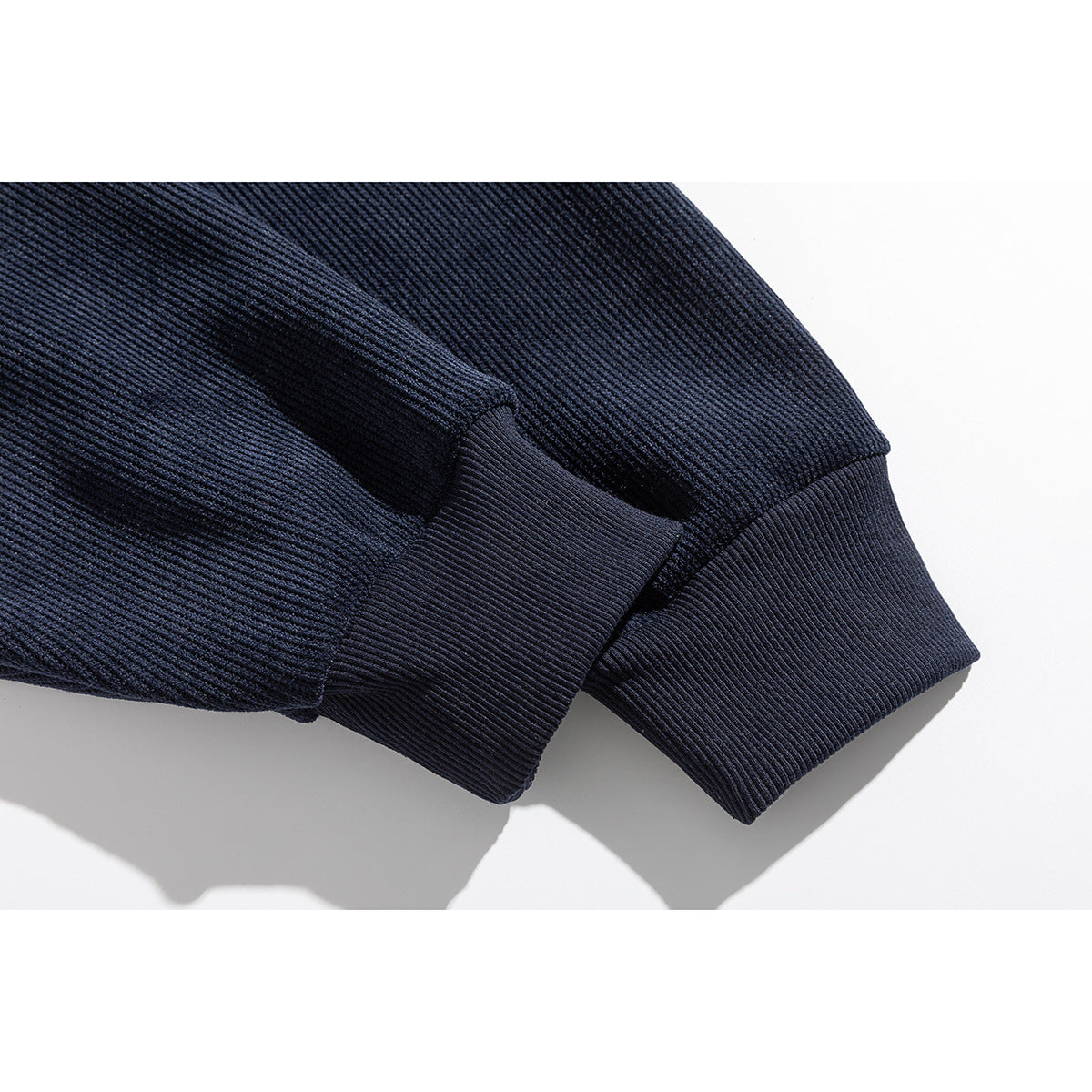 Close-up of a navy hoodie sleeve ending in a wide ribbed cuff.