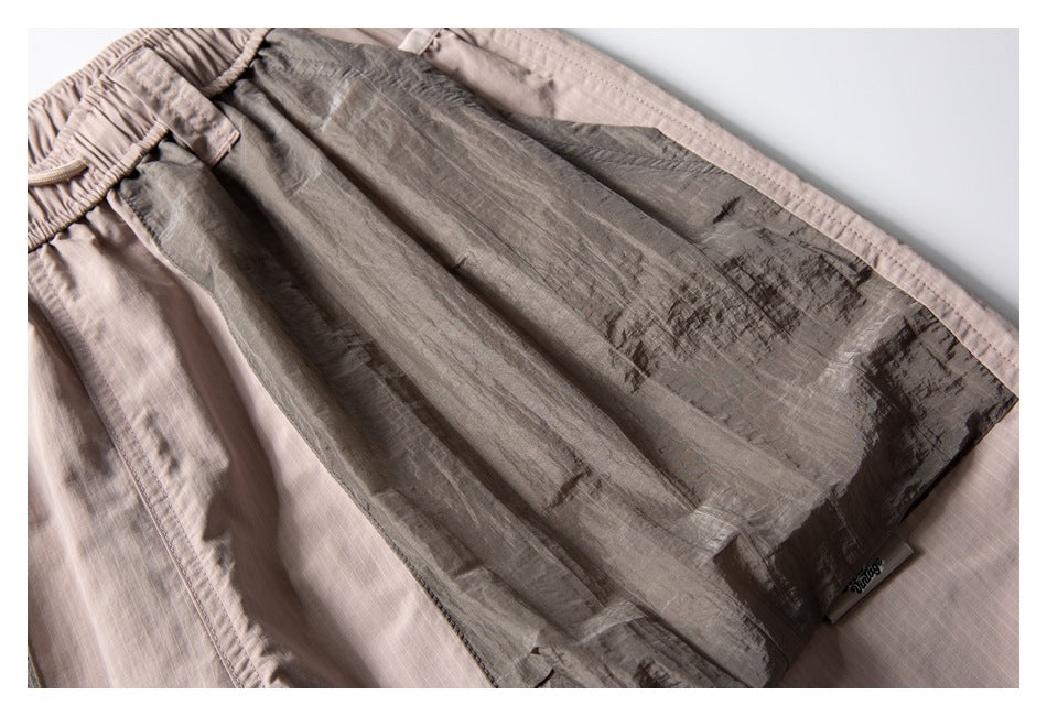 Close-up of light taupe shorts with a darker contrasting fabric panel.