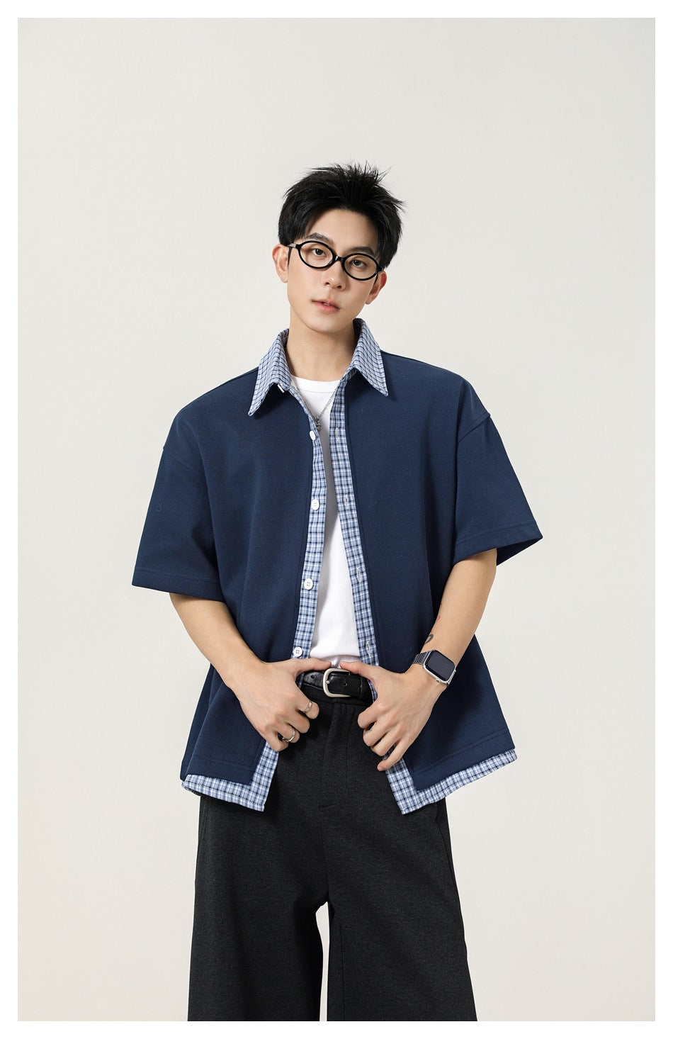 Front view of a model wearing a navy short-sleeve shirt with blue plaid collar, placket and hem trim.