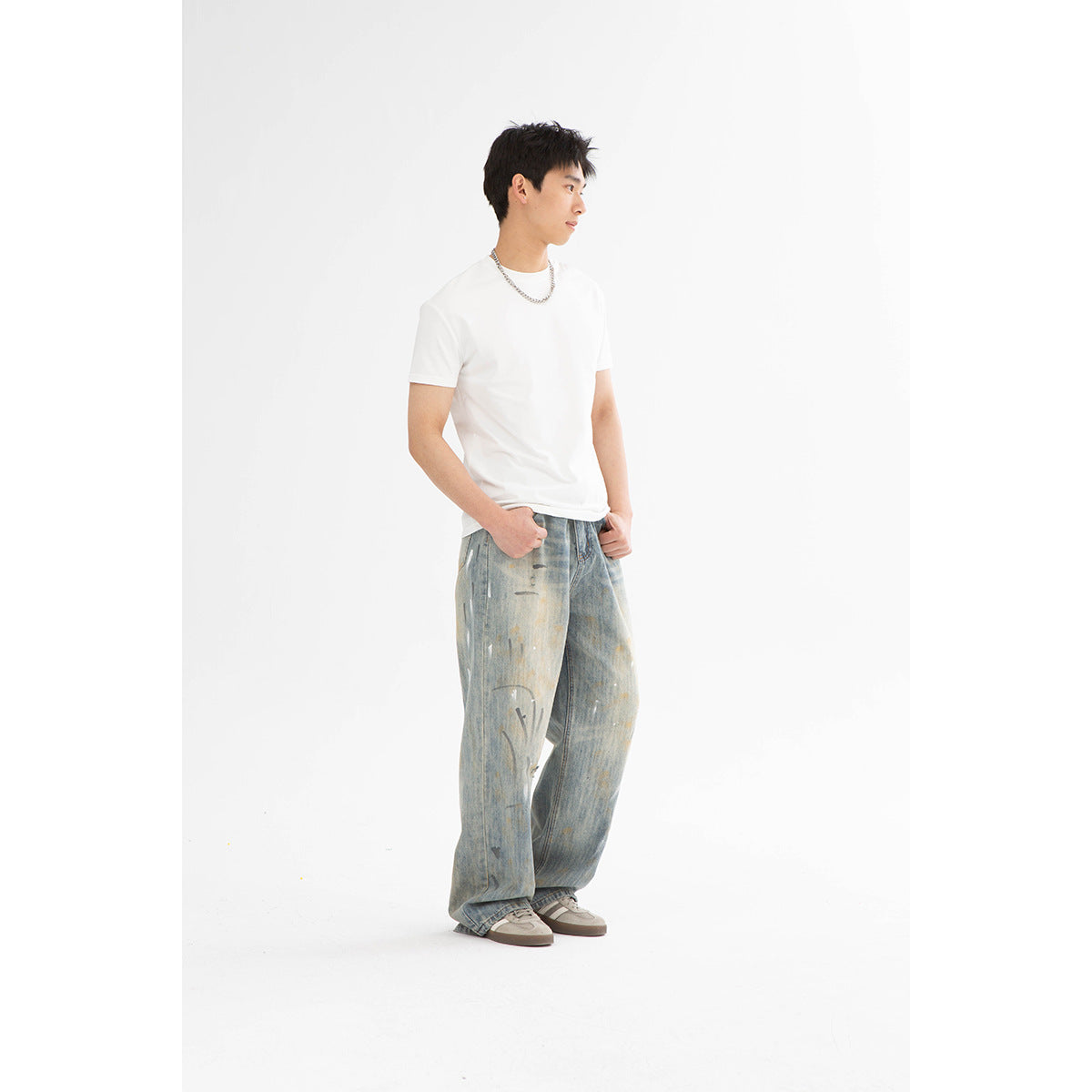 Side-profile model wearing a white crew-neck T-shirt and distressed, loose light-wash jeans.