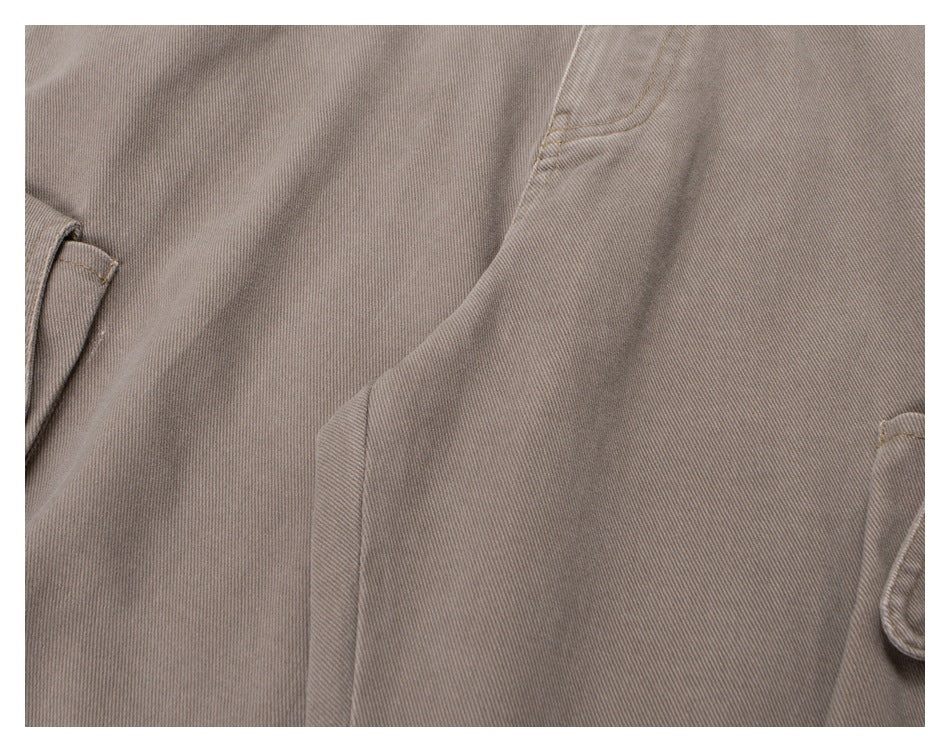 Close-up of taupe trouser fabric and stitching around a curved seam and pocket edge.