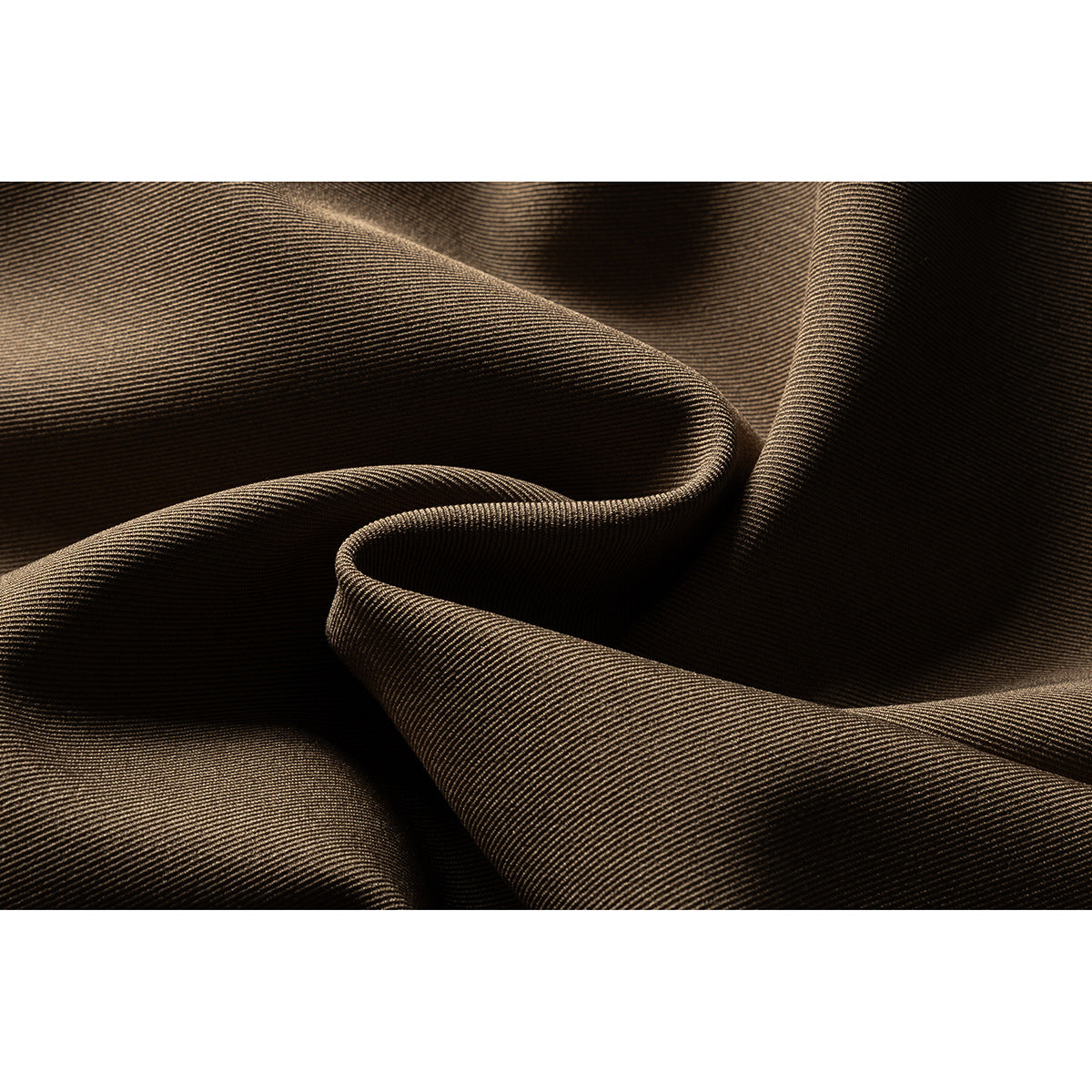 Macro view of brown fabric gathered into folds, showing its fine diagonal weave.