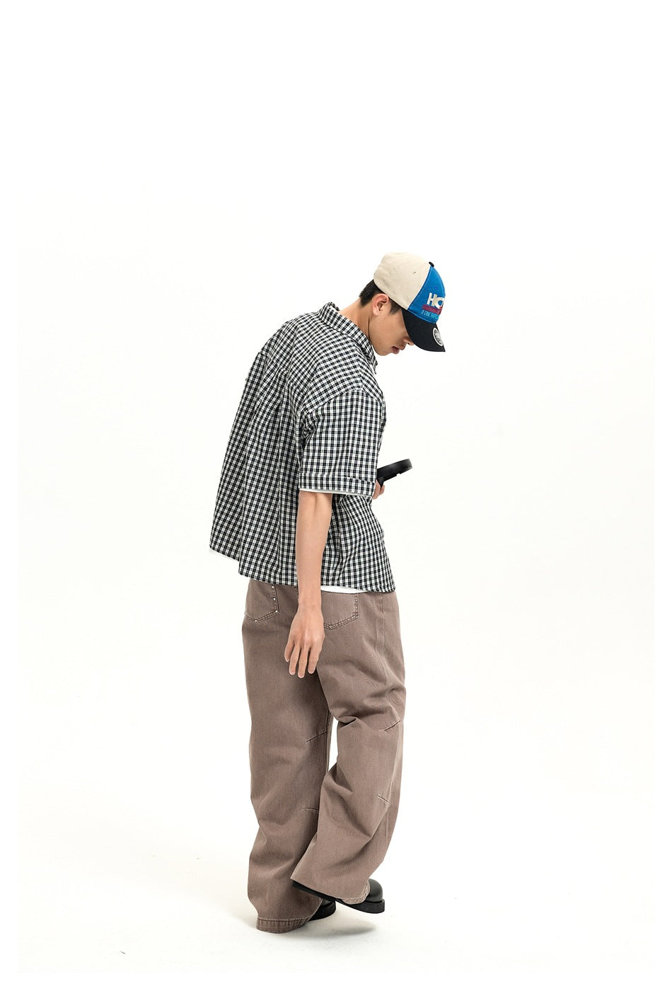 Side view of a model wearing dusty taupe wide-leg jeans and a black-and-white check shirt.