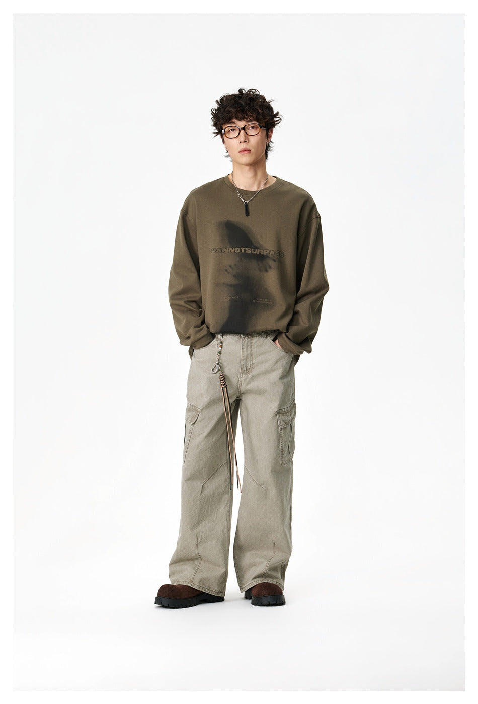Full-length model wearing an olive graphic sweatshirt and loose light cargo pants.