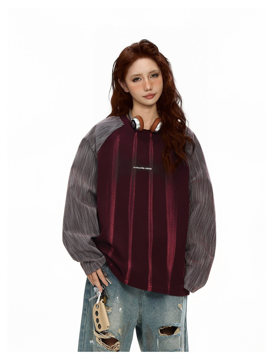 Close-up of model in a purple raglan crew-neck sweatshirt with striped sleeves and headphones around the neck