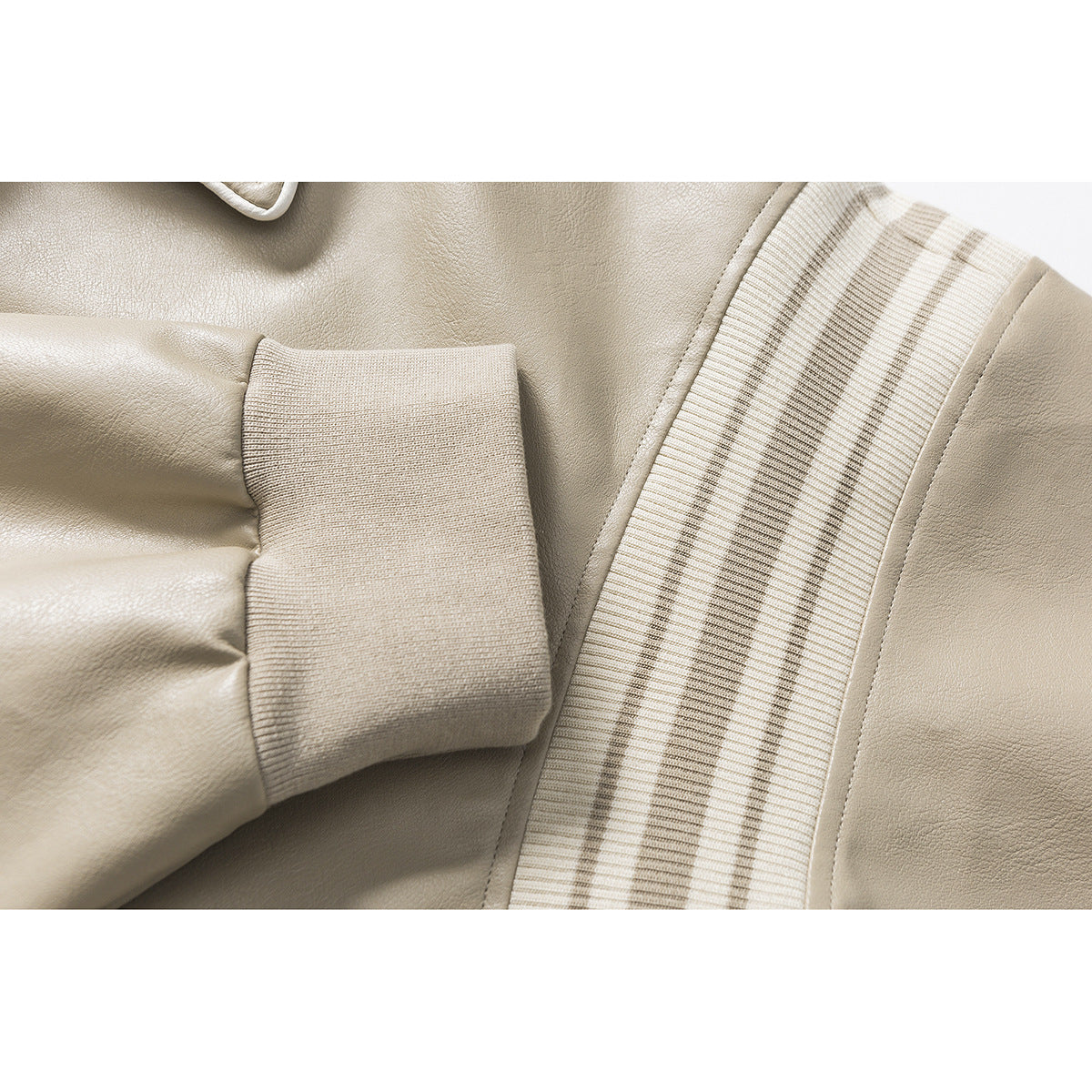 Close-up of a light taupe jacket sleeve, ribbed cuff, and cream striped trim panel.