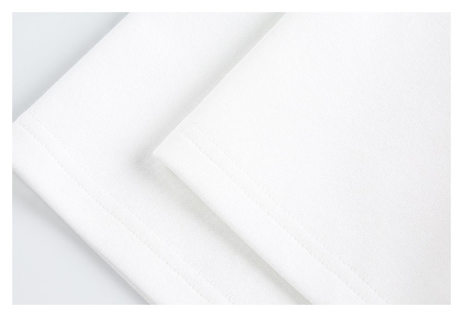Close-up of overlapping white garment panels and their stitched edges.