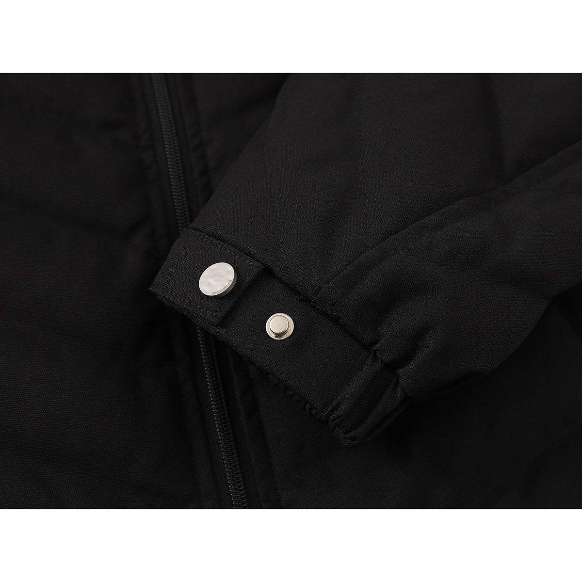Close-up of a black jacket sleeve cuff with two silver-tone snap fasteners.