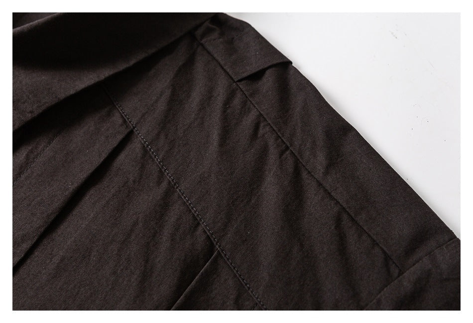 Close-up of a dark garment's shoulder seam and overlapping fabric panels.
