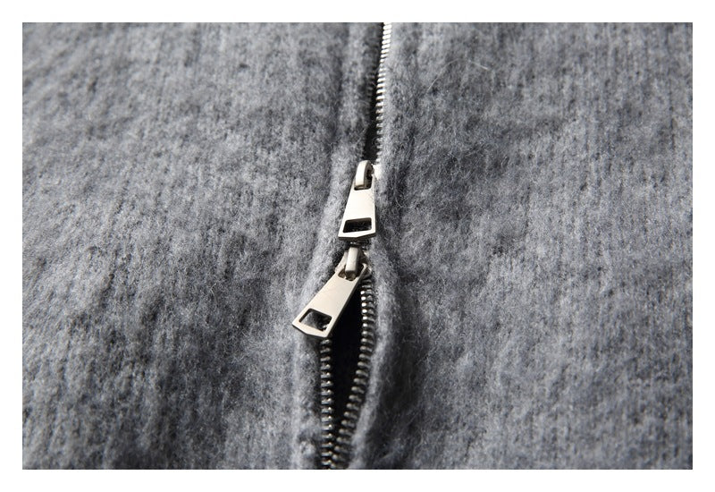 Close-up of the cardigan's metal zipper with two sliders on gray fuzzy fabric.