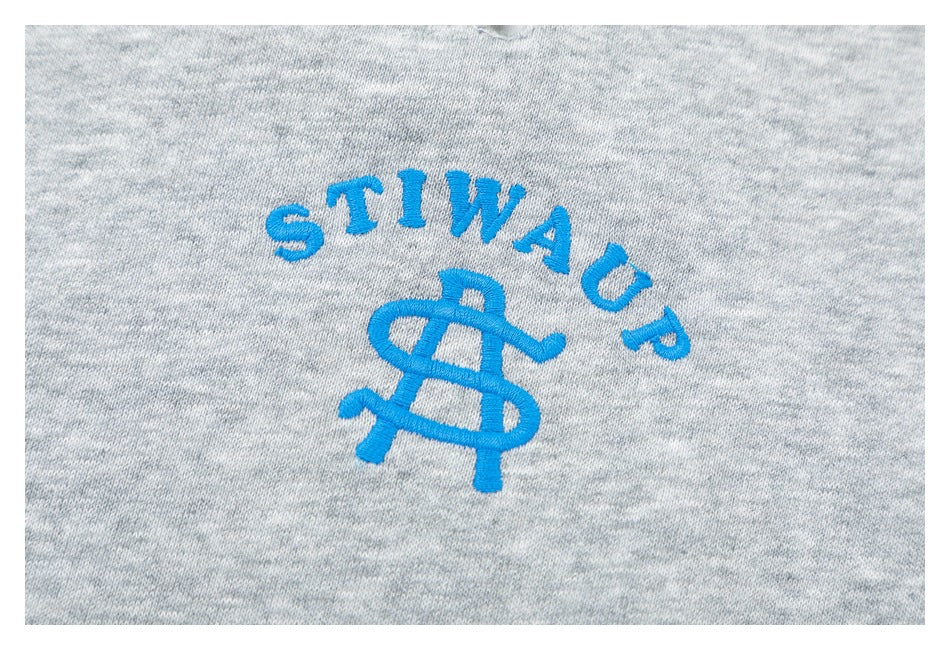 Close-up of blue embroidered lettering and a monogram on heather gray fabric.