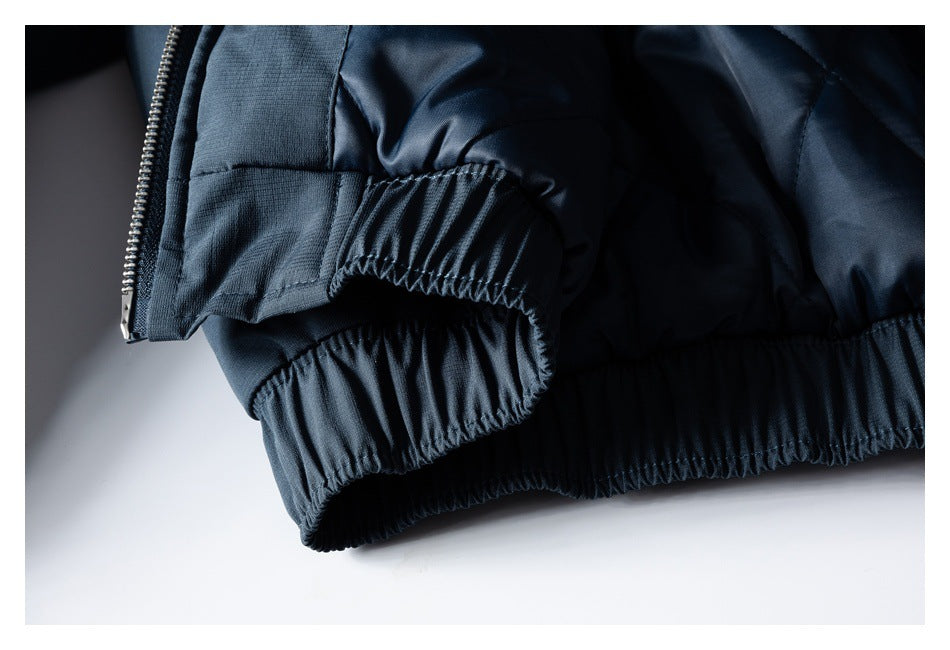Close-up of a dark navy jacket hem and sleeve cuff with gathered elastic edging and a zipper.