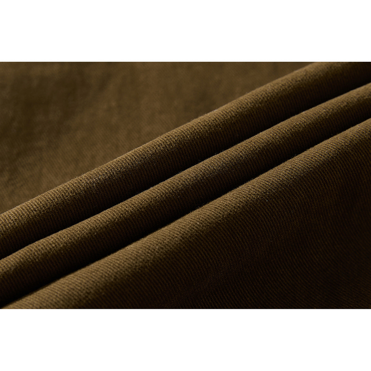Macro view of dark brown trouser fabric arranged in soft folds, showing its fine textured weave.