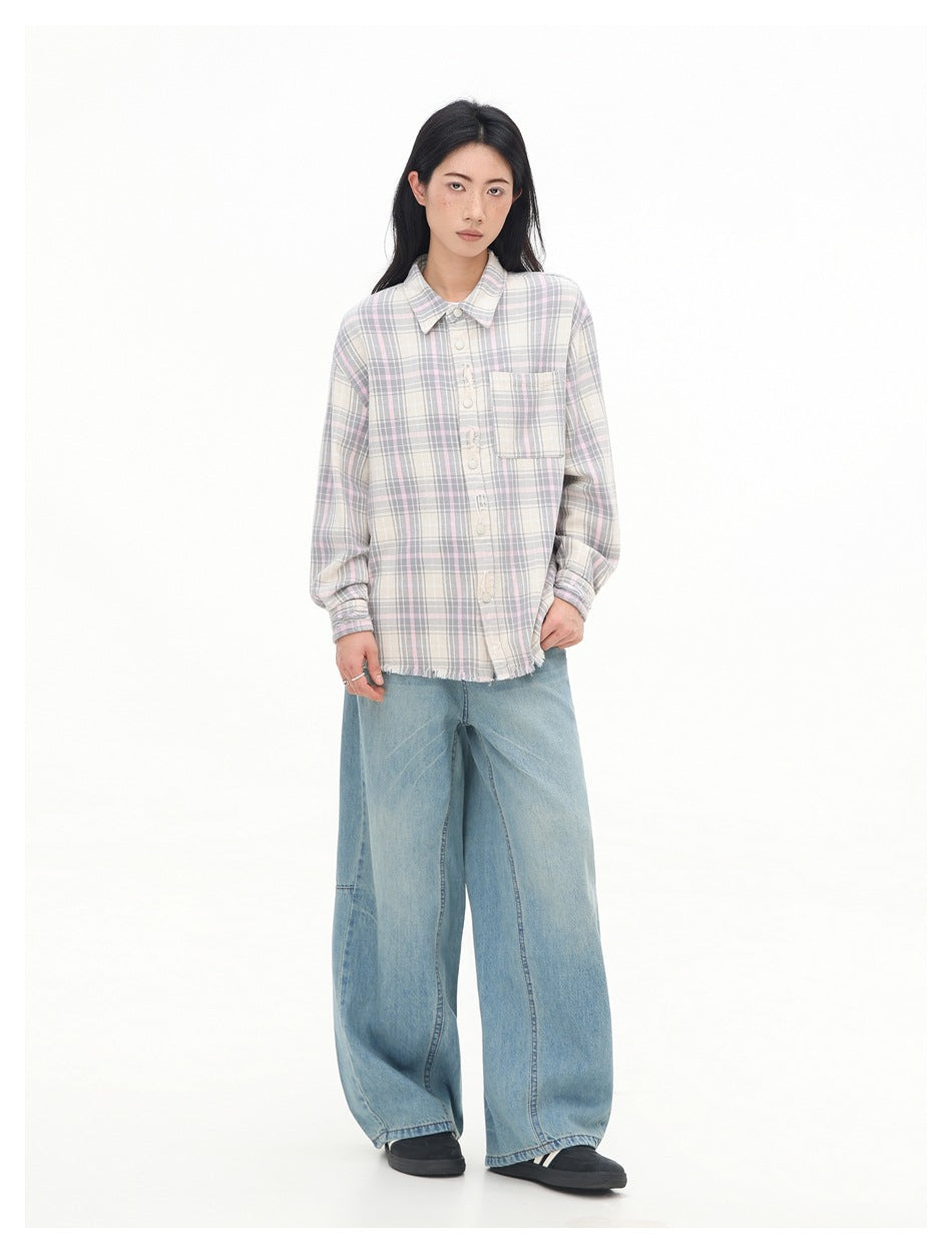 Full-length view of a model wearing a buttoned cream, gray and pale pink plaid shirt with a chest pocket.