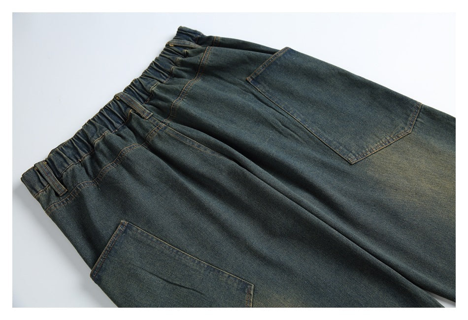 Angled flat lay of dark blue jeans showing an elasticated waistband, belt loops, and large front pockets.
