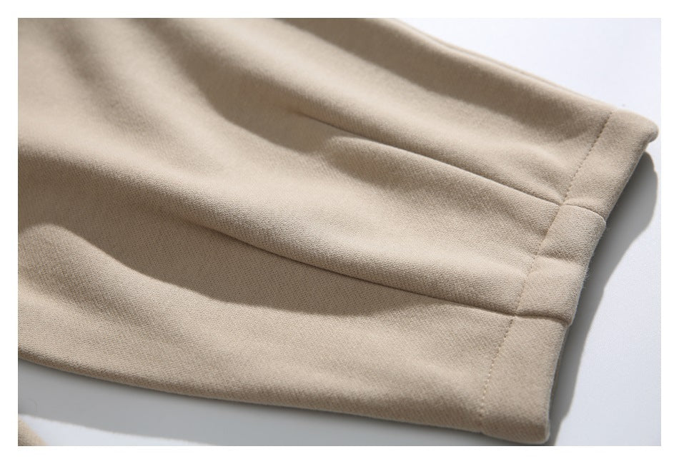 Close-up of a beige pants leg with a wide folded hem and visible stitching.