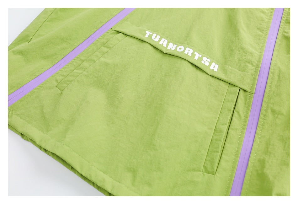 Close-up of a lime-green jacket pocket flap with white lettering and lavender zipper trim.