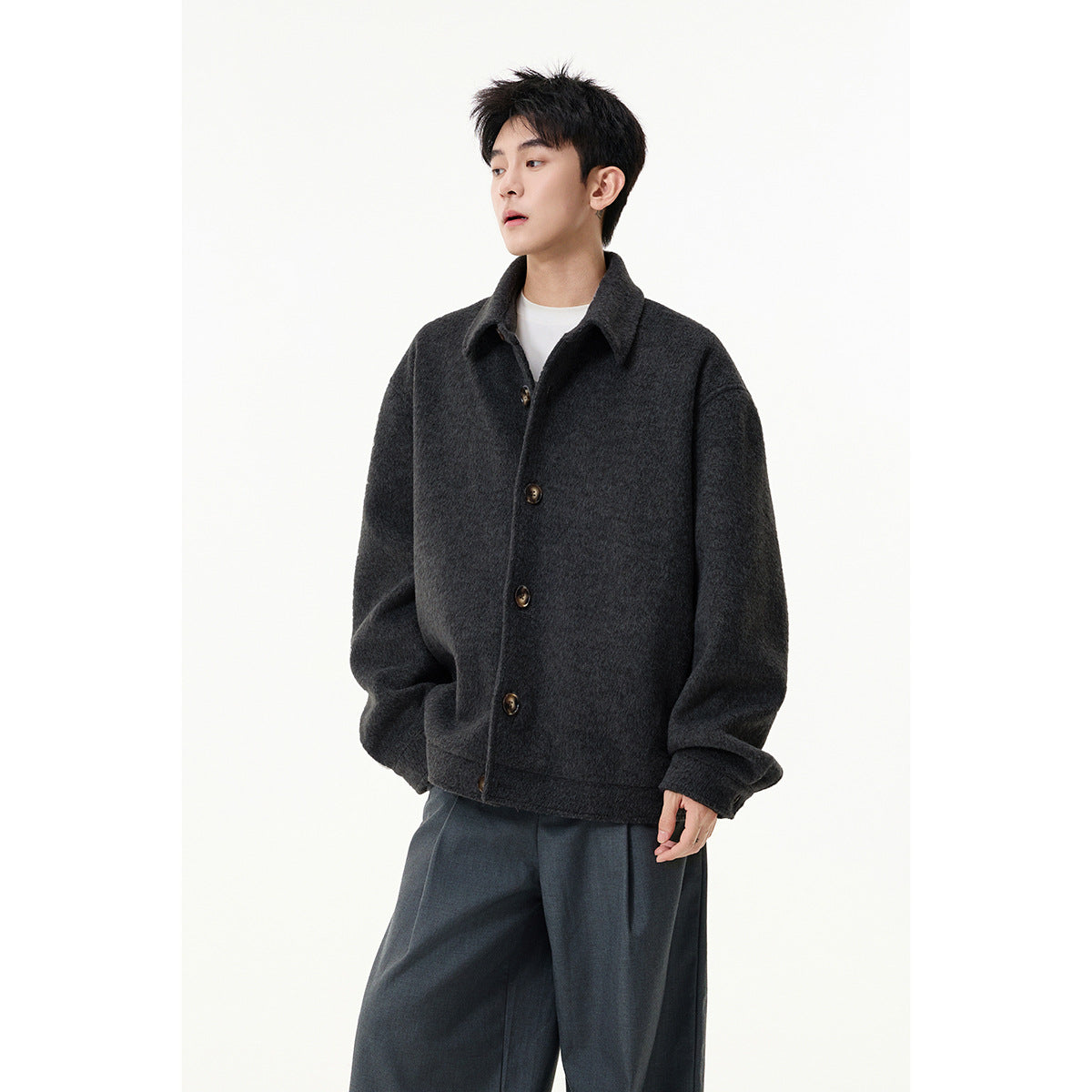 Front view of a person wearing an oversized charcoal collared jacket with dark buttons.