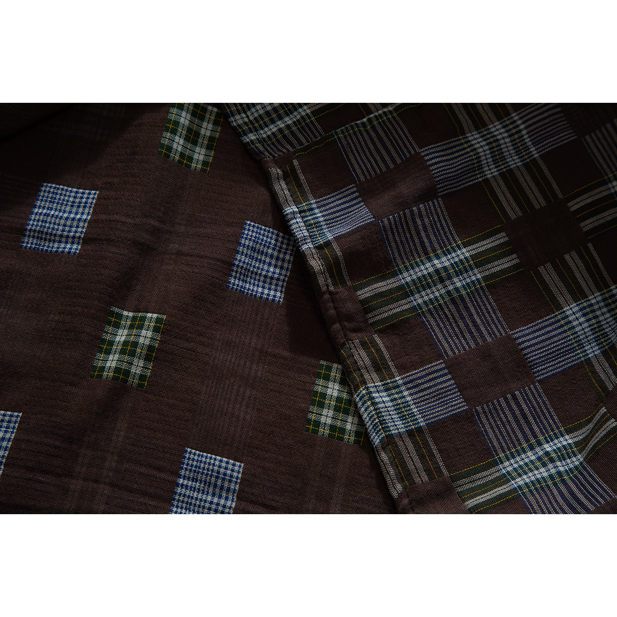 Close-up of brown shirt fabric with blue, green and cream plaid blocks and intersecting stripes.