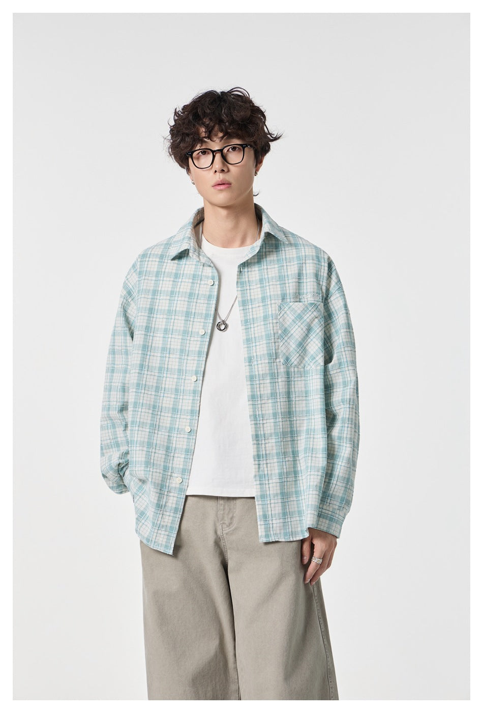 Waist-up view of a model in an open pale blue-and-white plaid button-up shirt with a chest pocket.