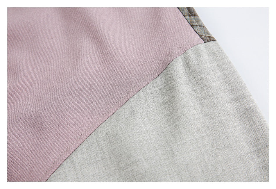 Close-up of a diagonal seam between a mauve jacket panel and a light gray panel, with plaid fabric at the edge.