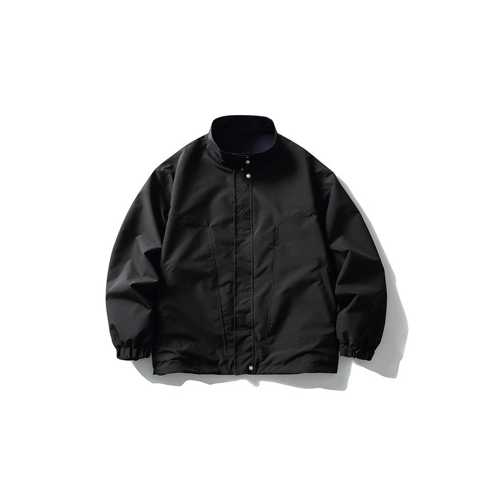 Front view of a black stand-collar jacket with a snap placket, panel seams, and gathered cuffs.