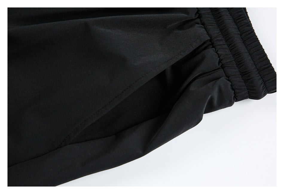 Close-up of black trousers showing the elastic waistband and a stitched side seam.