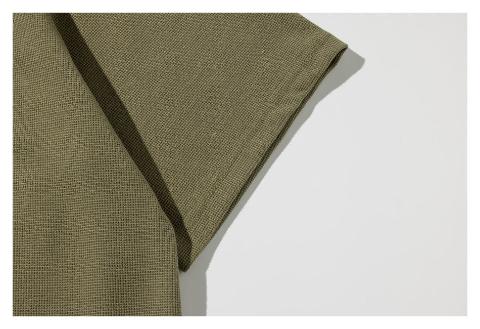 Close-up of the olive-green shirt’s short sleeve and stitched edge.