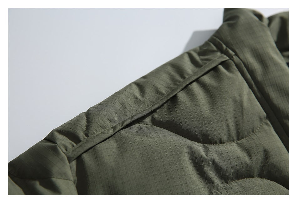 Close-up of the jacket's olive ripstop fabric and quilted shoulder seam.