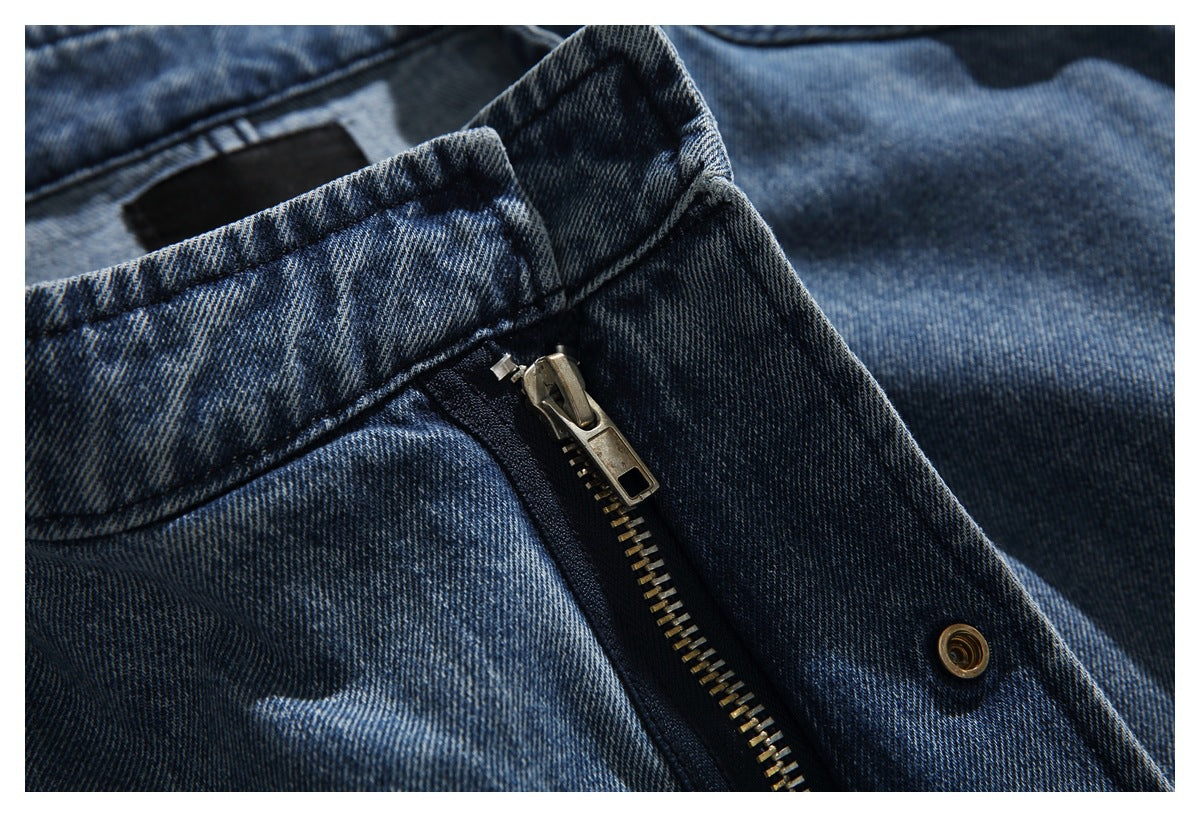 Close-up of a blue denim waistband with a metal zipper and snap closure.
