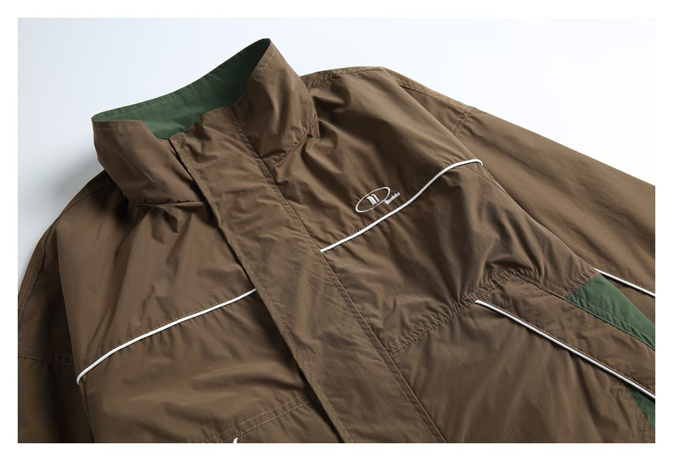 Close-up of a brown jacket's raised collar and chest, with green lining, white piping, and a small emblem.