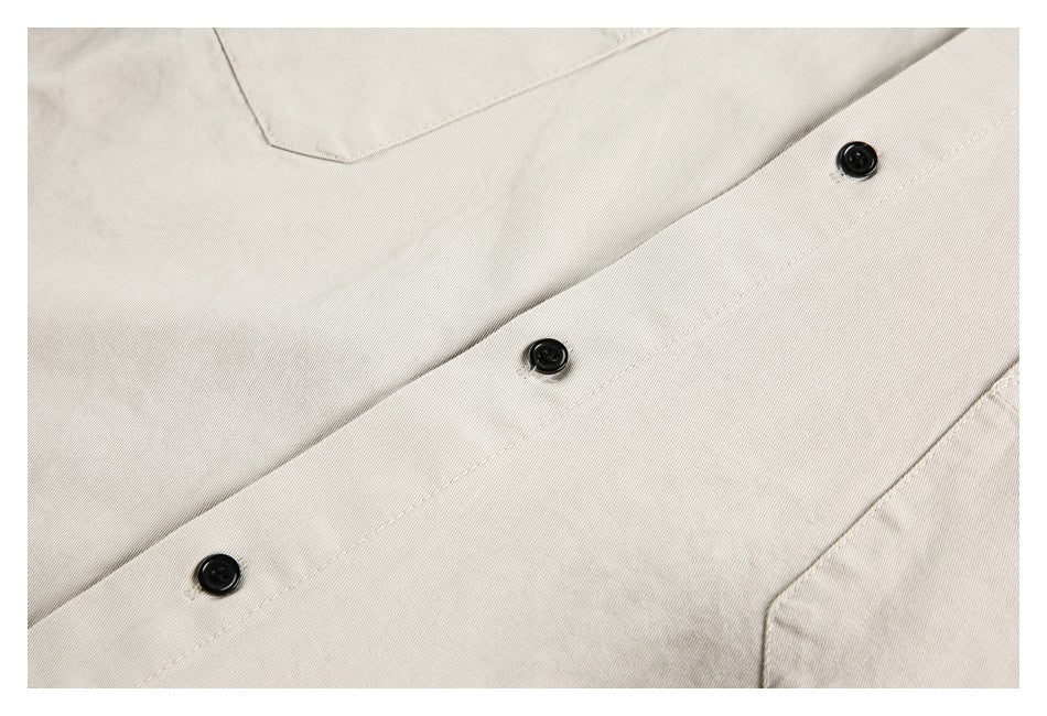 Close-up of beige shirt fabric, a button placket, and black buttons.