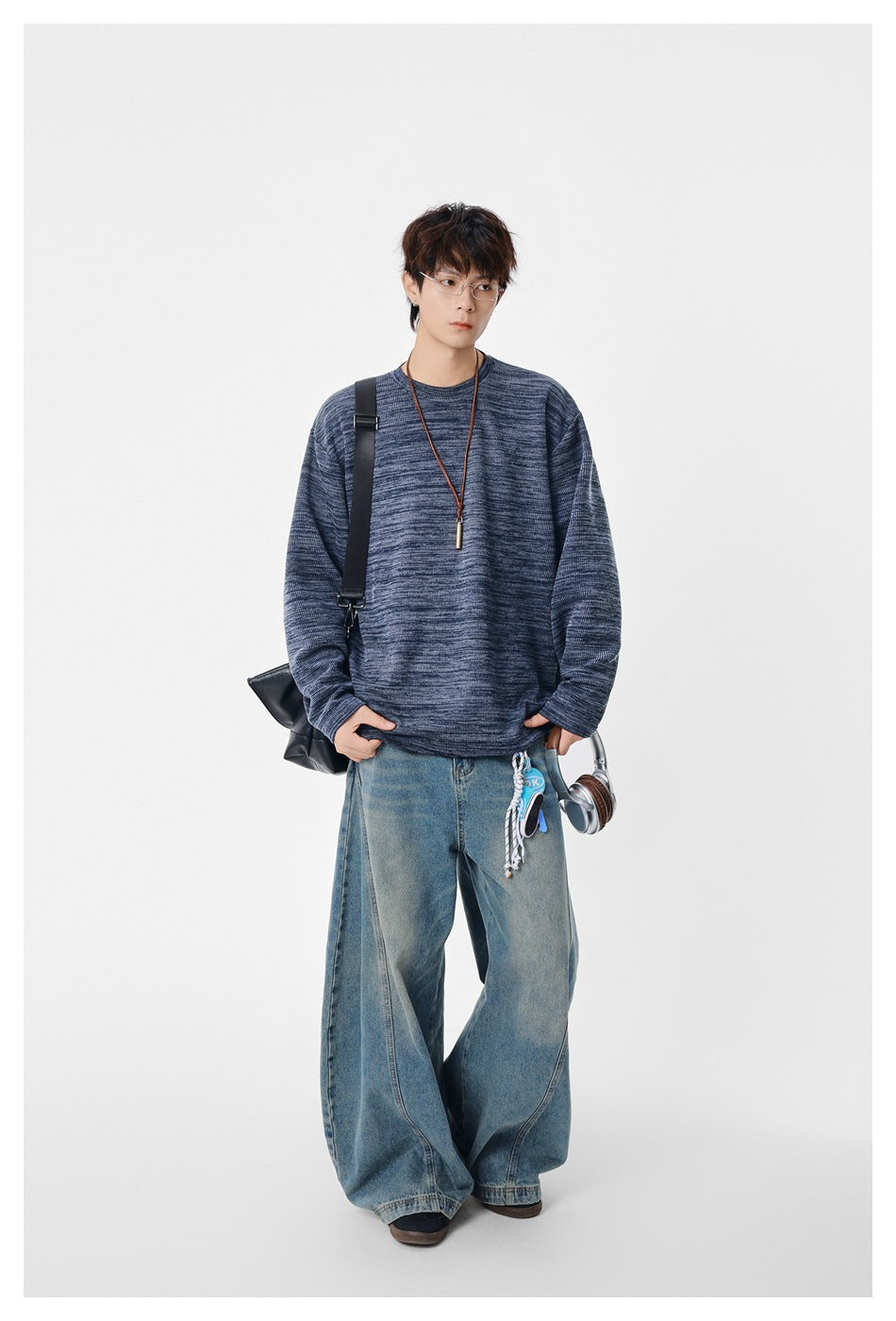 Model wearing a blue heathered crew-neck pullover with wide-leg jeans and a black shoulder bag, full-length view
