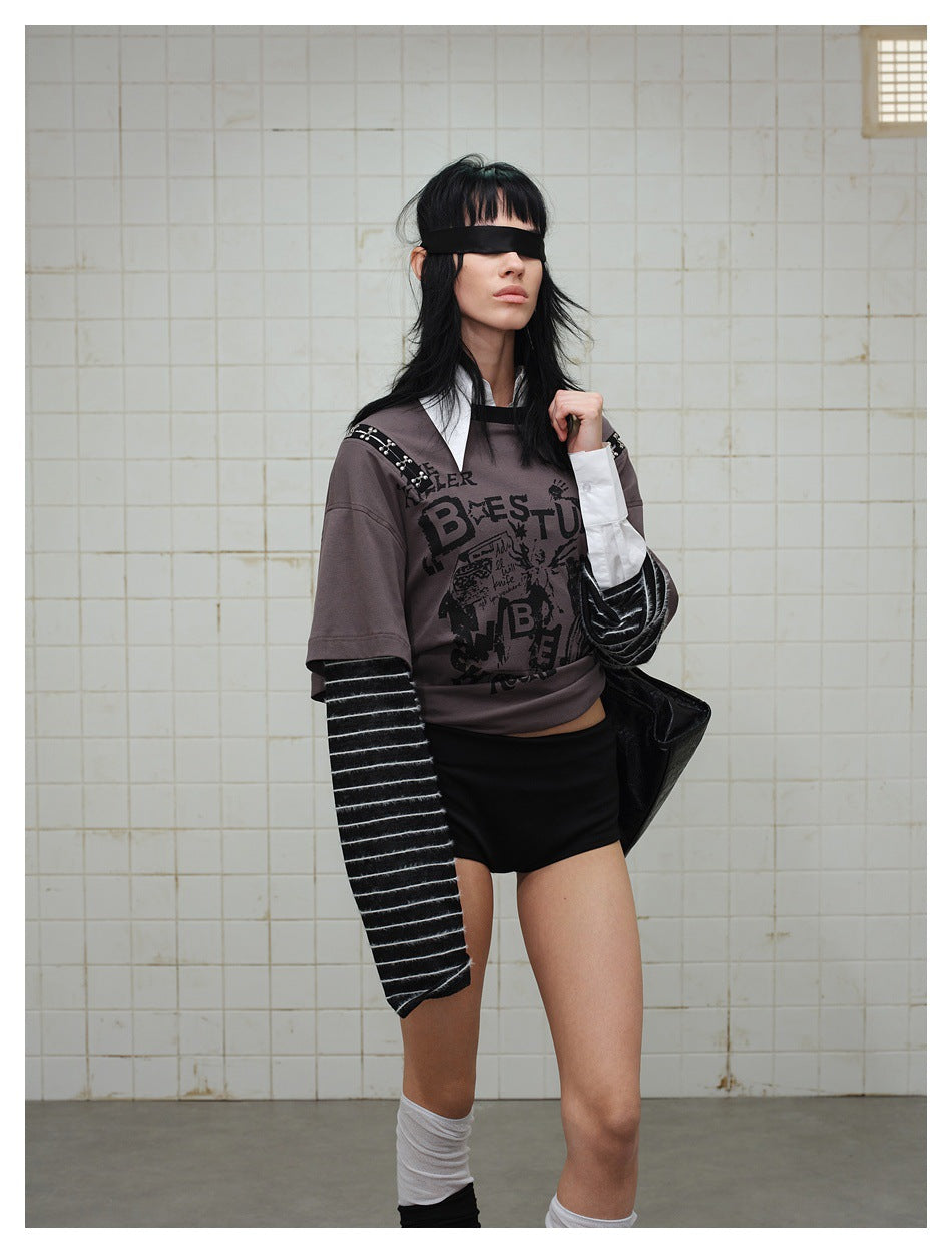 Model wearing a gray graphic top with long striped sleeves and black shorts, shown in a close full-body pose.