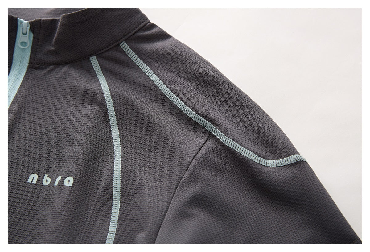 Charcoal top shoulder and chest detail with pale blue seam stitching and small pale lettering.