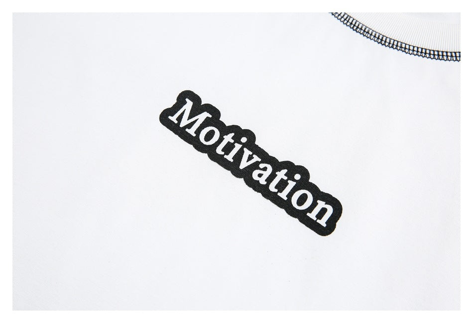 Close-up of white garment with black overlock stitching and black-and-white “Motivation” print.