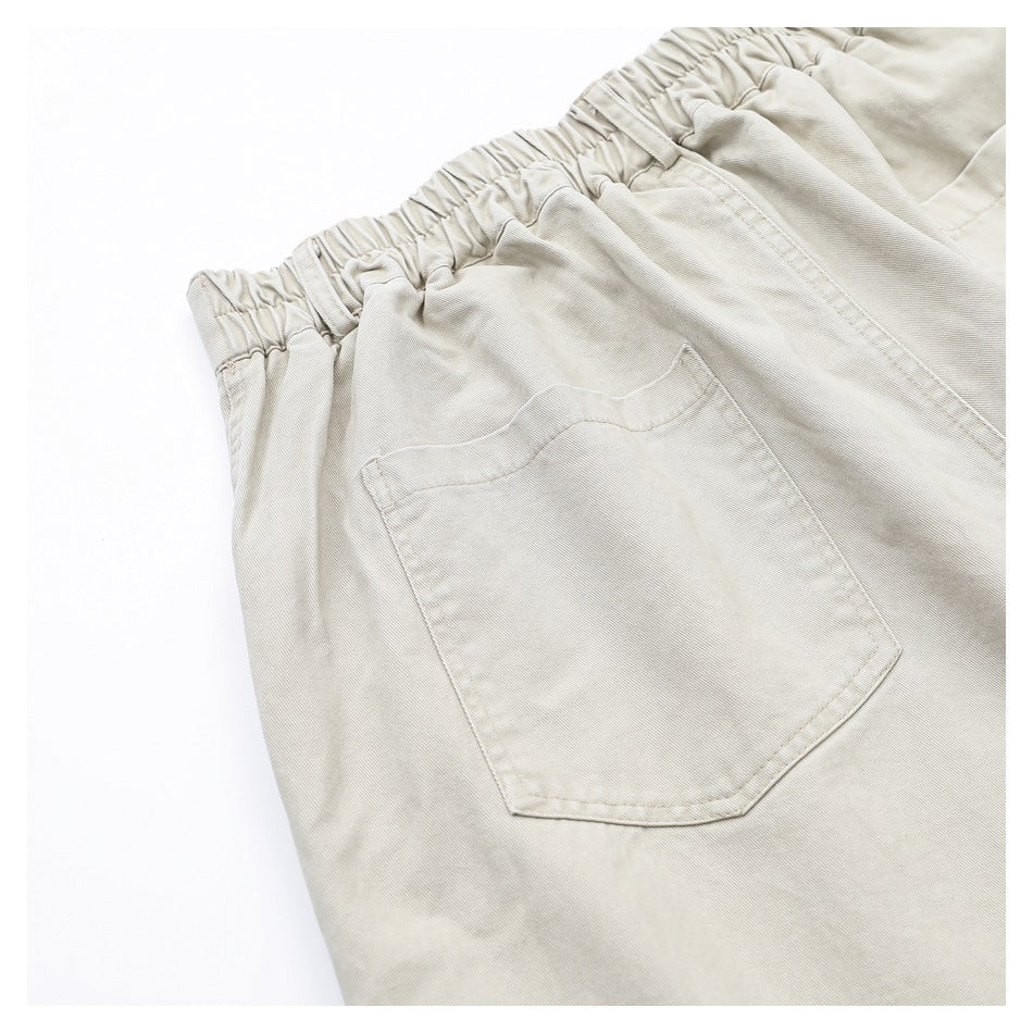 Close-up of light beige pants showing an elasticized back waistband and a patch pocket.
