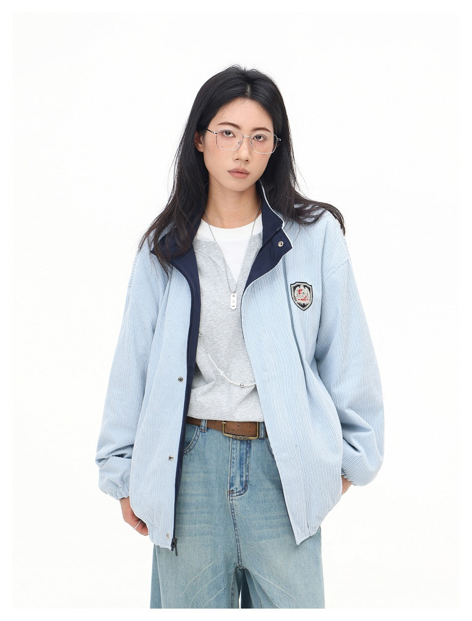 Front view of a model in a pale blue ribbed jacket with a navy collar, chest crest, and front pockets.