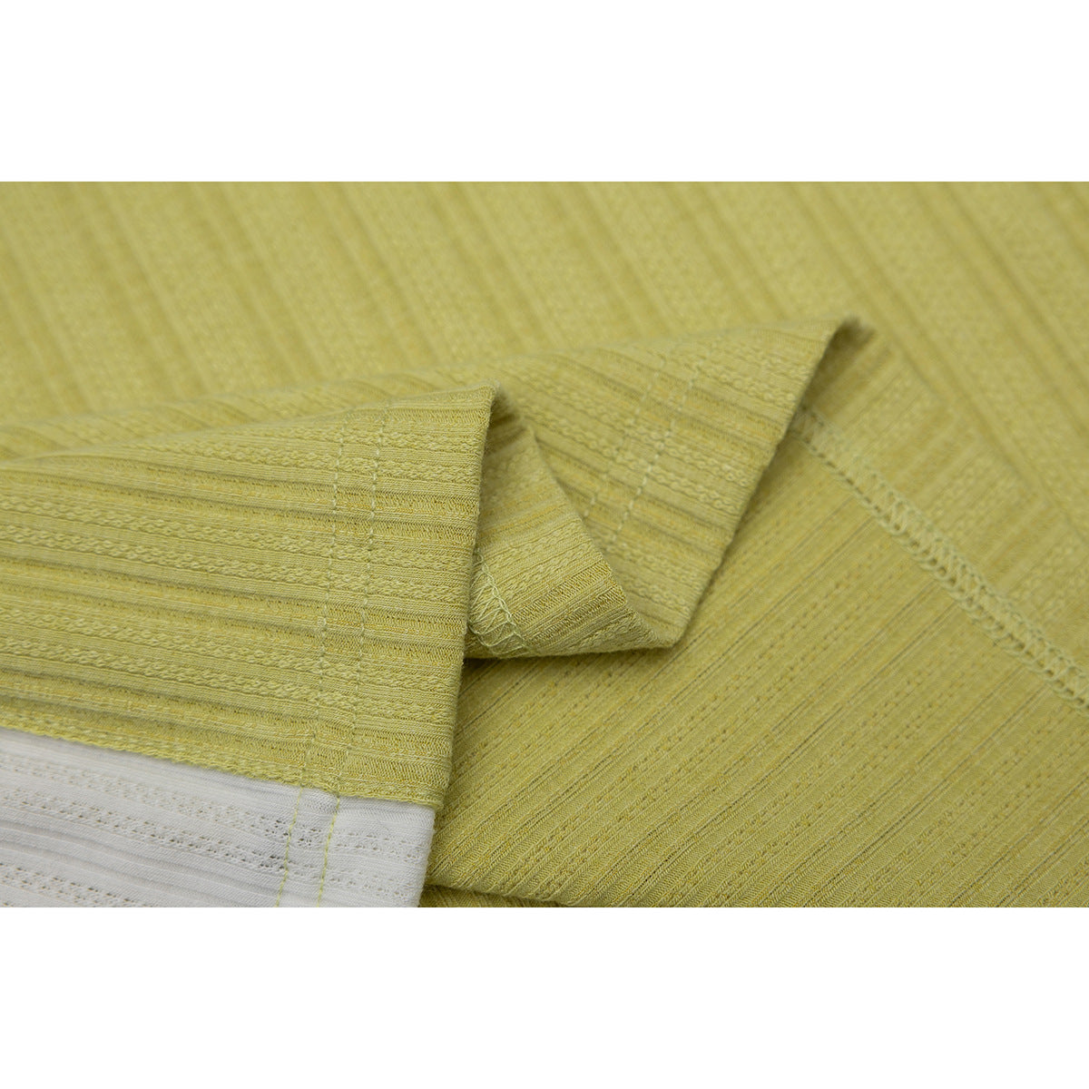 Close-up of lime-yellow shirt fabric, a folded short sleeve, stitching, and a white side panel.