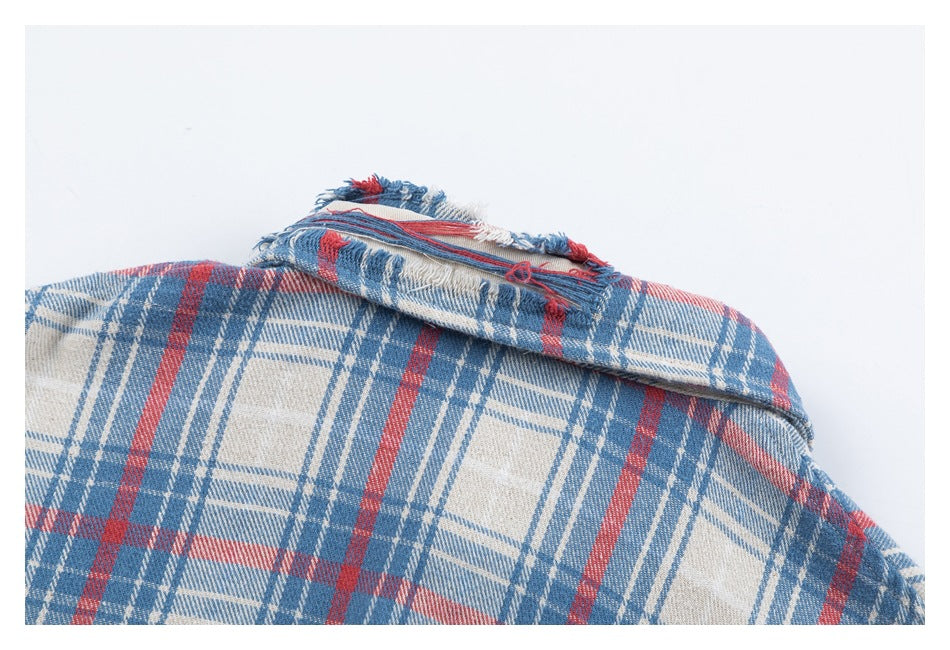 Close-up of a blue, red, and cream plaid garment collar with a frayed edge.