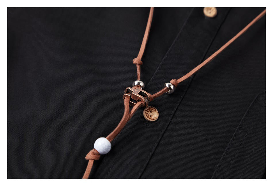 Close-up of a brown cord necklace with metal and bead accents resting on black garment fabric.