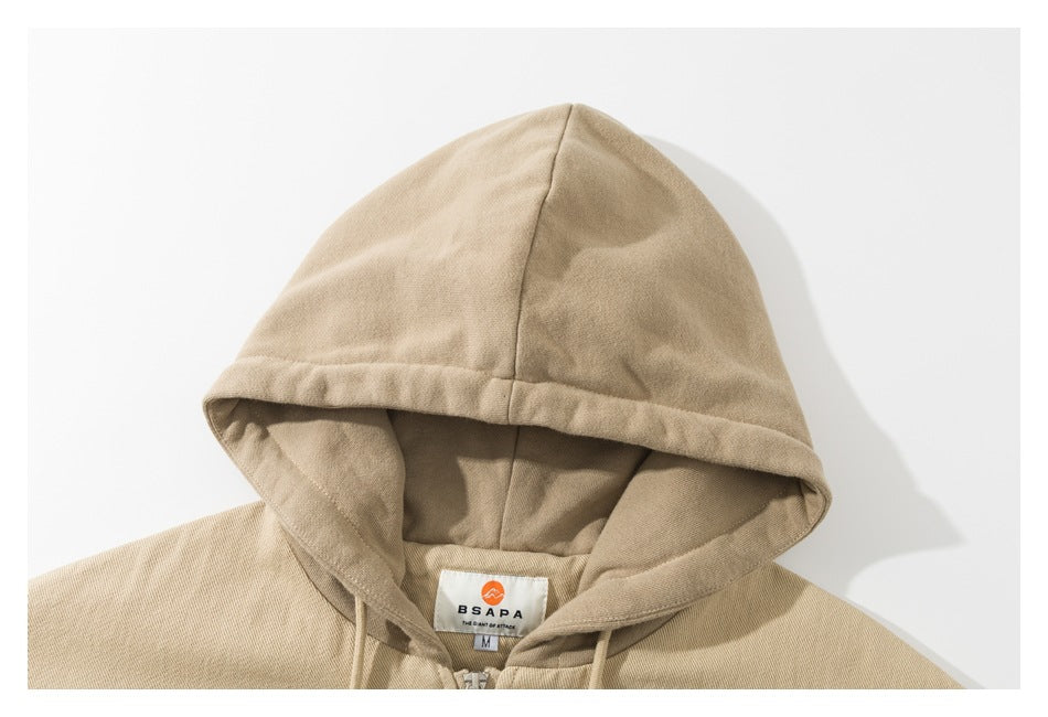 Close-up of a beige hooded jacket showing the hood, drawstrings, and neck label.
