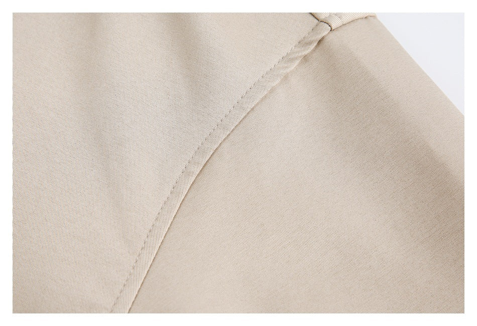 Close-up of a curved stitched seam on the beige jacket.
