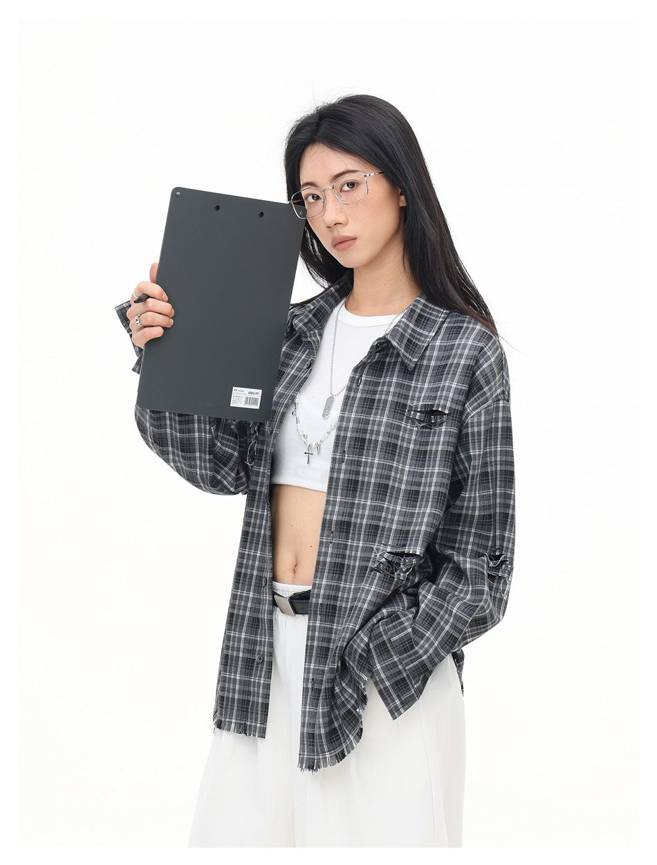 Model wearing open gray plaid distressed shirt over a white crop top, holding a dark clipboard