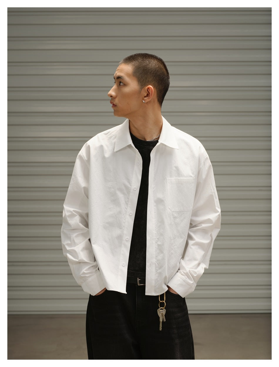 Model wearing a white long-sleeve button-up shirt with a chest pocket, viewed at an angle.